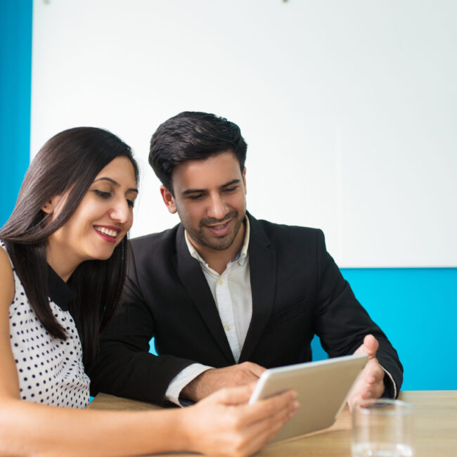 Portrait of happy young colleagues using digital tablet Portrait of happy young colleagues using digital tablet. Young Caucasian businessman and businesswoman sitting at table and watching data on pc tablet. Wireless technology in business